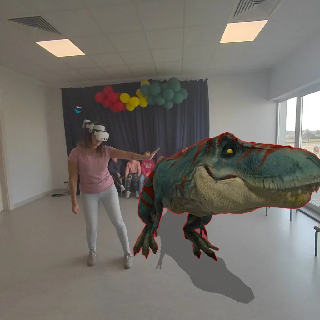 Dziewczynka w goglach VR wyciąga rękę w stronę wirtualnego dinozaura w Gnieźnieńskim Ośrodku Sportu i Rekreacji