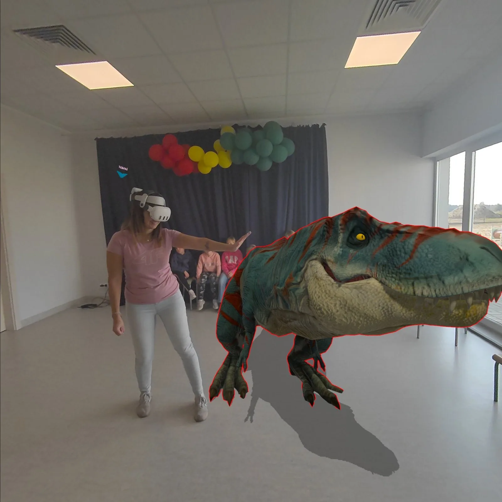 Dziewczynka w goglach VR wyciąga rękę w stronę wirtualnego dinozaura w Gnieźnieńskim Ośrodku Sportu i Rekreacji