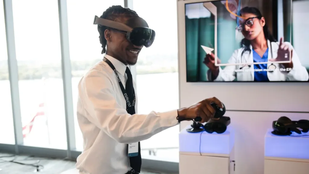 Attendee wearing a Quest Pro headset beside a monitor showing a training presentation at the Meta Future of Work Summit