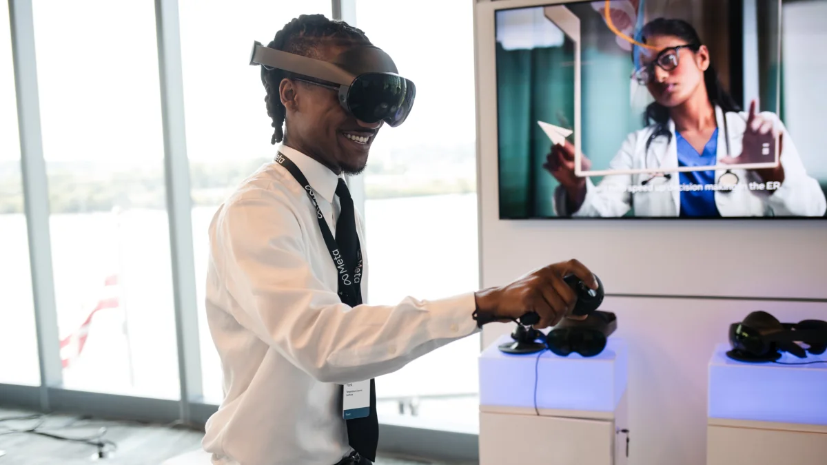 Attendee wearing a Quest Pro headset beside a monitor showing a training presentation at the Meta Future of Work Summit