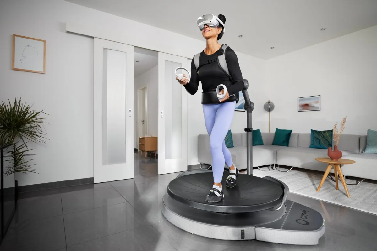 A woman standing on a Virtuix Omni One platform in the harness